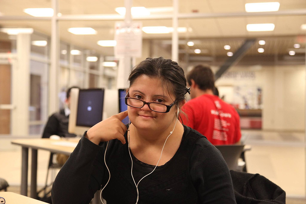 A student with glasses looks to the camera